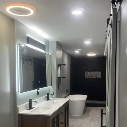 Contemporary bathroom with lit mirrors and tub
