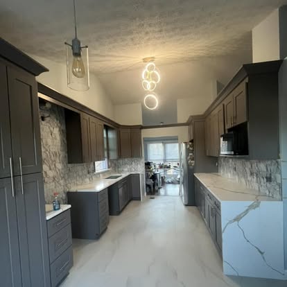 Dark cabinet kitchen with large counters and pendant light